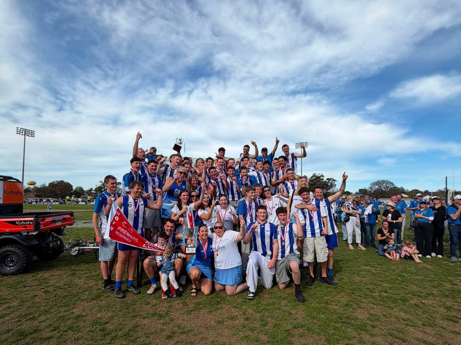 Heyfield footballers and netballers celebrating with their premiership cups